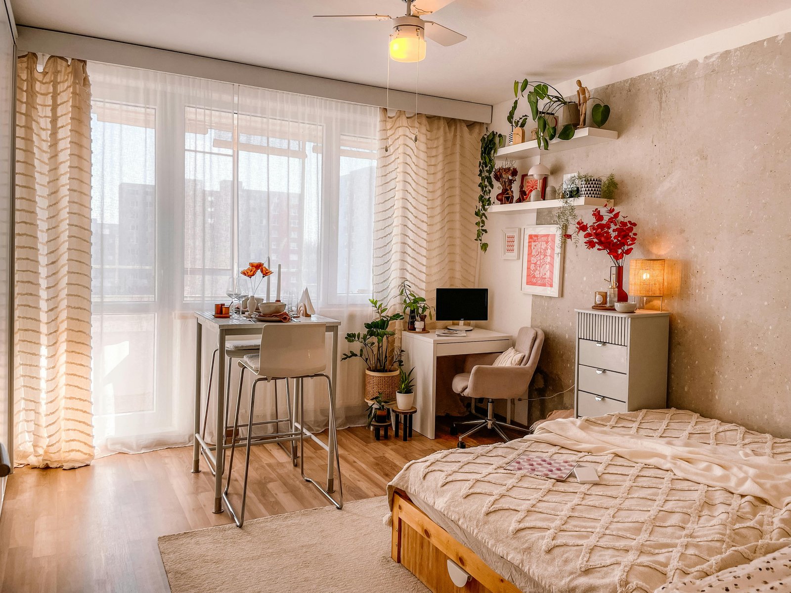 Calm apartment bedroom with layered linen bedding, pale walls, and soft daylight.